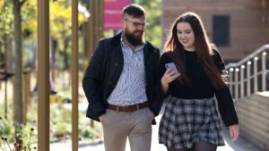 Two students chatting while walking through campus.