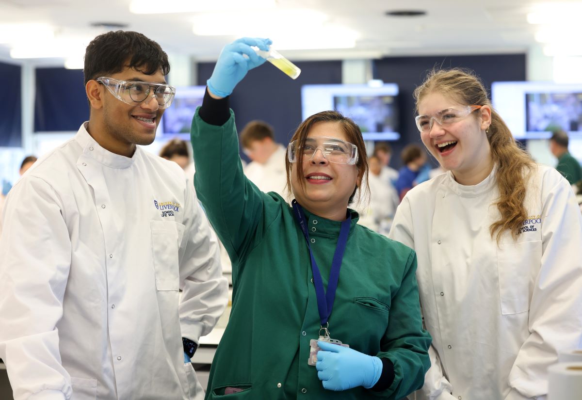 Three students look at a test tube in a lab.