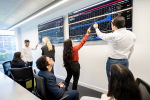 Management School students in conversation in the McKenzie Trading Suite at the Management School