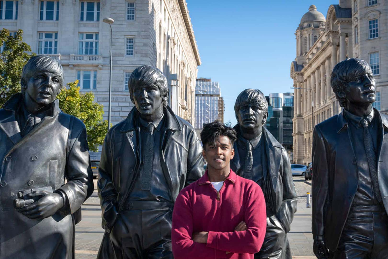 A student stands in front of a sculpture of The Beatles on Liverpool's waterfront.