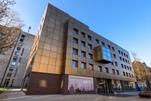 An image of the outside of the School of Law and Social Justice Building. A large, gold and modern building.