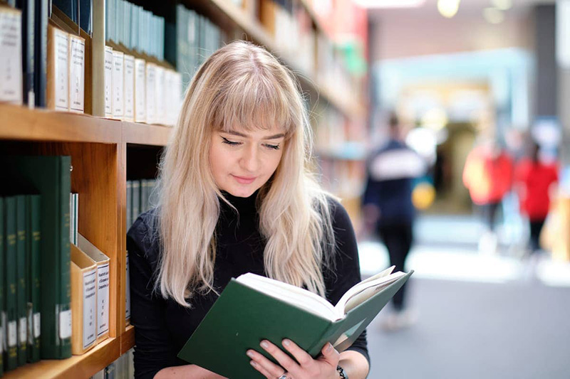 Student looking at a book in the library