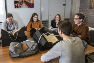 Two male and two female students around a table with a male academic reviewing documents from the University's special collections