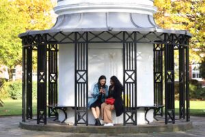 Two students sitting outside in the green space on Abercromby Square.