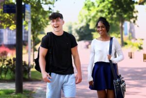 Two students chatting while walking through campus.